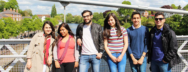 Mehrere Erwachsene stehen auf einer Brücke in Chester mit der Stadt im Hintergrund