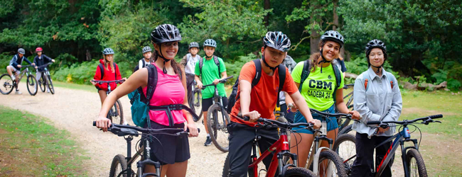 Schüler mit Helm fahren Mountainbike in einem Wald in England
