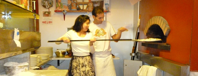 Ein Pizziolo erklärt einer Frau, wie man eine Pizza in einem Holzofen backt, während einer LISA! Sprachreise Italienisch