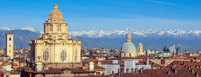 Blick über die Dächer von Turin mit der Cappella della Sindone und den schneebedeckten Alpen im Hintergrund, ideal für eine LISA! Sprachreise Italienisch