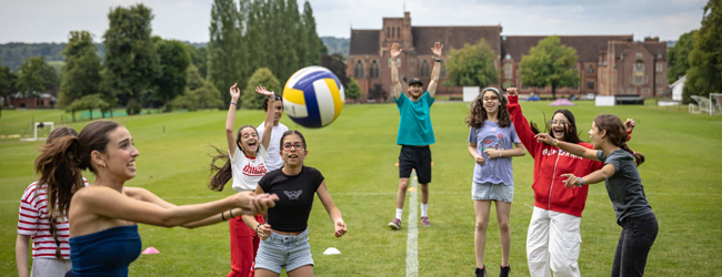 Mehrere Schüler spielen Volleyball auf einem Rasen vor der Sprachschule in Ardingly