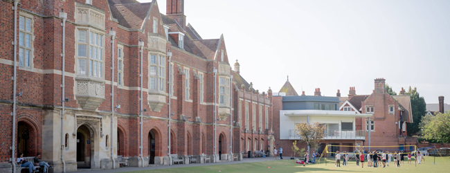 Vor der Sprachschule bei einer Sprachreise für Schüler in Eastbourne Rotes Backsteingebäude mit Rasenfläche und Kindern im Volleyballspiel in Eastbourne beim Sprachkurs