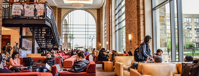 In einer Lounge mit Sesseln sitzen Studenten und lernen